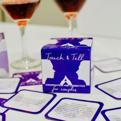 Touch & Tell Card Game with cards spread out, two glasses of wine in background
