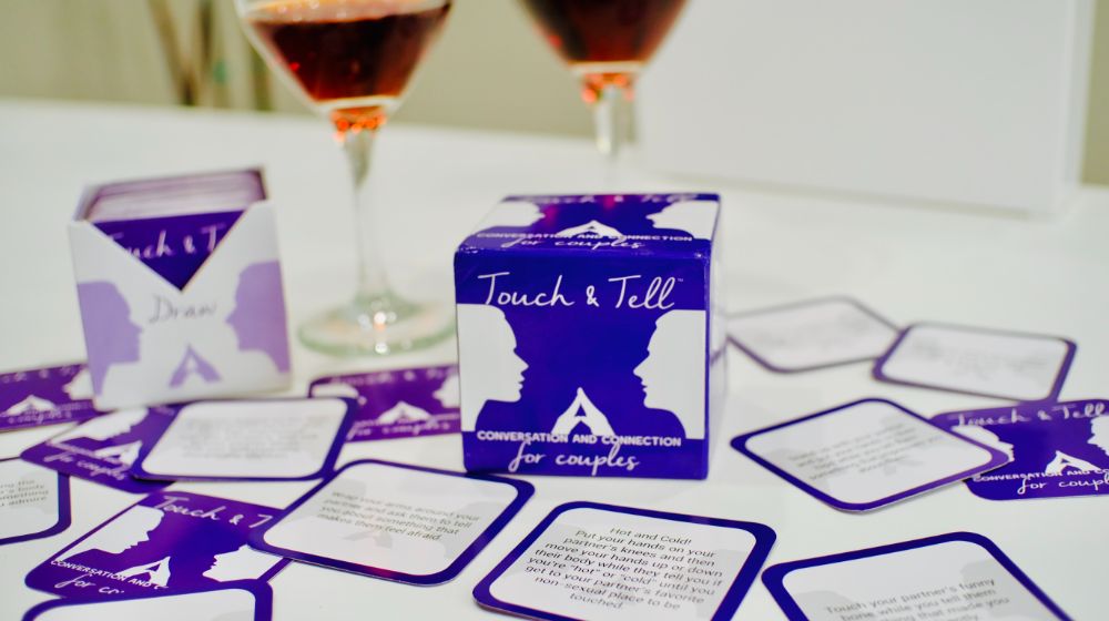 Touch & Tell Card Game with cards spread out, two glasses of wine in background